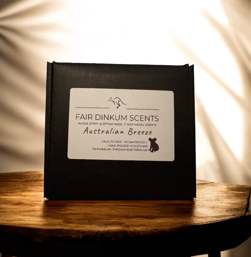 Black packaging of Fair Dinkum Scents Australian Breeze on a wooden surface with a warm light background.