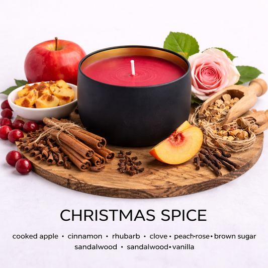 Candle labelled 'Christmas Spice' with apples, cinnamon, and a rose on a wooden board by Fair Dinkum Scents.